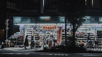 Night street view of Japanese drugstore with shoppers and bicycles