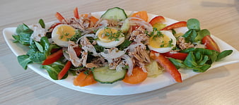 Fresh tuna salad with hard-boiled eggs, cucumber, and vegetables on a white plate
