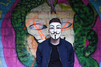 Man in Guy Fawkes Mask Against Colorful Graffiti Wall