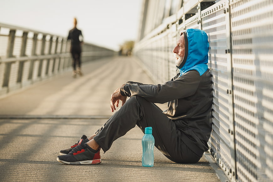 Senior man resting after running on bridge