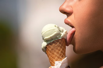 Close-up of woman licking green ice cream cone