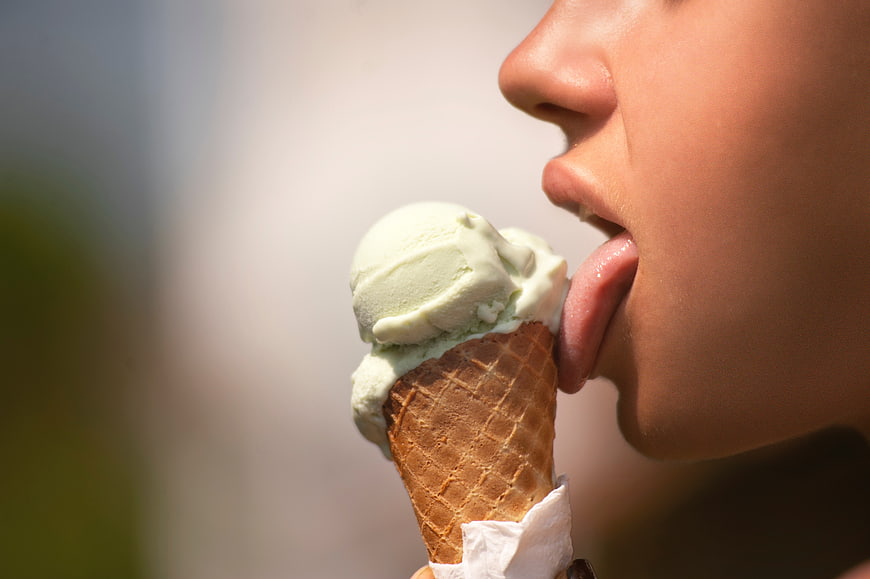 Close-up of woman licking green ice cream cone