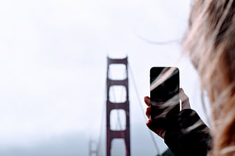 Woman taking photo of Golden Gate Bridge with smartphone