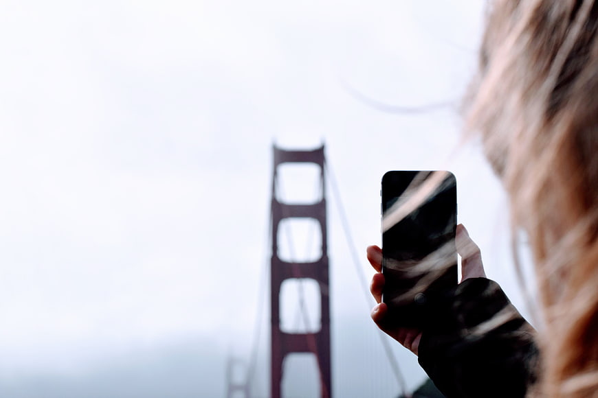 Woman taking photo of Golden Gate Bridge with smartphone