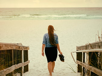Woman Walking Down Wooden Stairs to White Sandy Beach