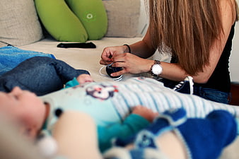 Mother tying baby shoes on couch