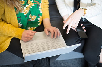 Two women collaborating on a laptop in a modern office setting