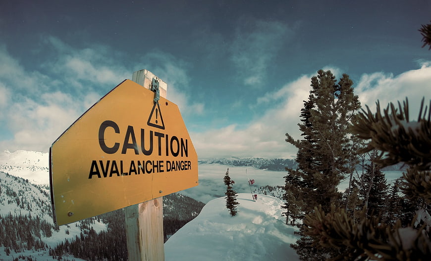Yellow Caution Avalanche Danger Sign in Snowy Mountain Landscape