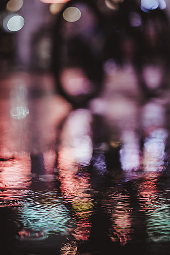 Abstract colorful city lights reflecting in rain puddles at night