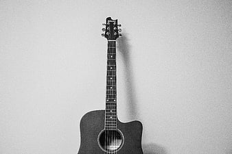 Black and White Acoustic Guitar Leaning Against White Wall