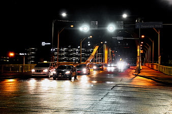 Night traffic on wet bridge with city lights and cars