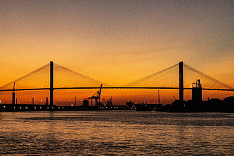 Silhouette of cable-stayed bridge at sunset over water