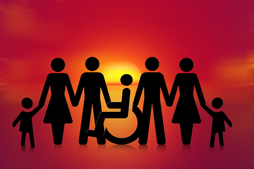 Silhouette of inclusive family with wheelchair user at sunset