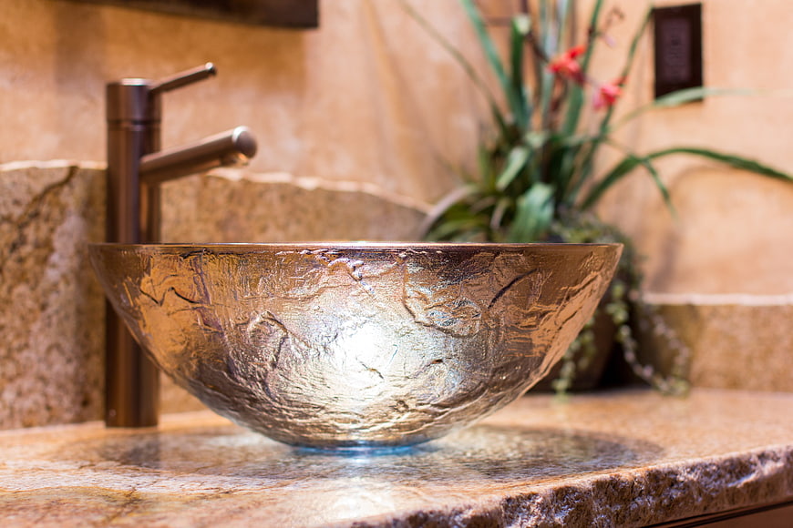 Luxurious hammered metal vessel sink in warm modern bathroom interior