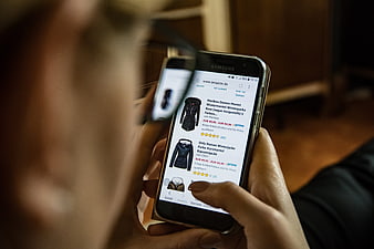 Woman browsing winter jackets on smartphone online shopping