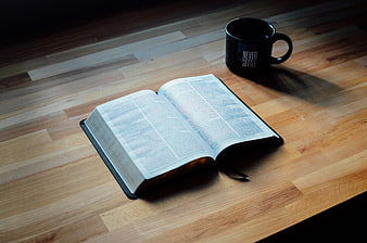 Open Bible and Black Mug on Wooden Table