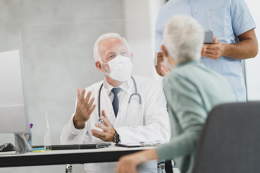Senior Doctor Consulting with Elderly Patient in Clinic