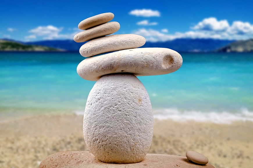 Stacked Zen Stones on Beach with Blue Ocean Background