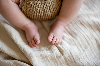 Close-up of baby feet on beige blanket with knitted toy