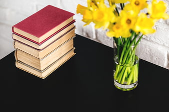 Stack of Books and Yellow Daffodils on Black Table