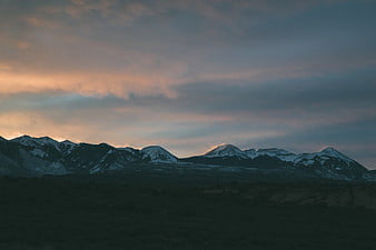 Snow-Capped Mountain Range at Dusk with Dramatic Clouds