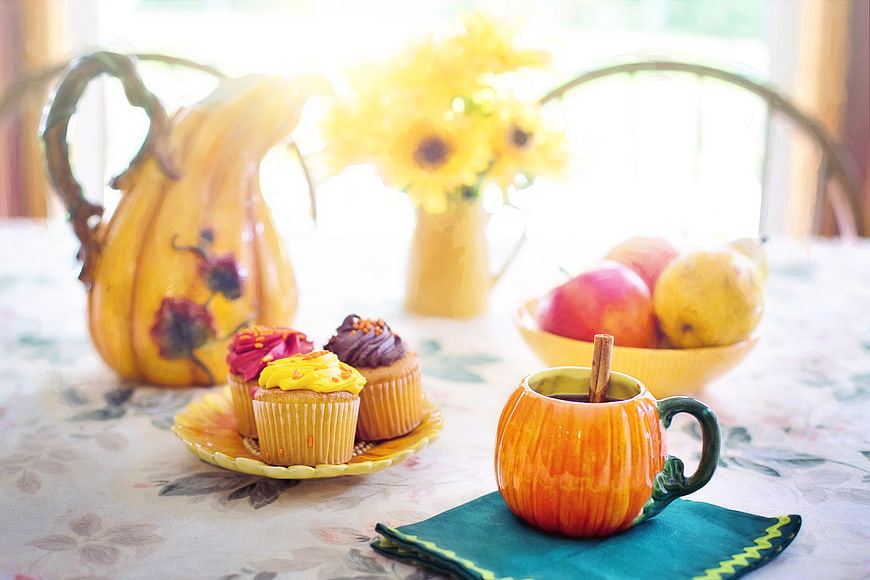 Autumn table setting with pumpkin mug, cupcakes, and fruit