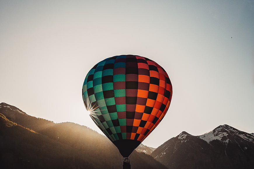 Colorful Hot Air Balloon Silhouette Against Mountain Sunrise
