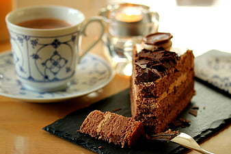 Slice of chocolate cake with tea cup on slate