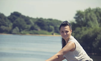 Smiling Woman Cycling by Lake on Sunny Day