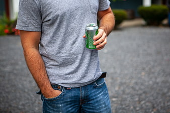 Man holding green beverage can outdoors