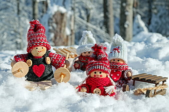 Cute wooden dolls in knitted hats playing in winter snow