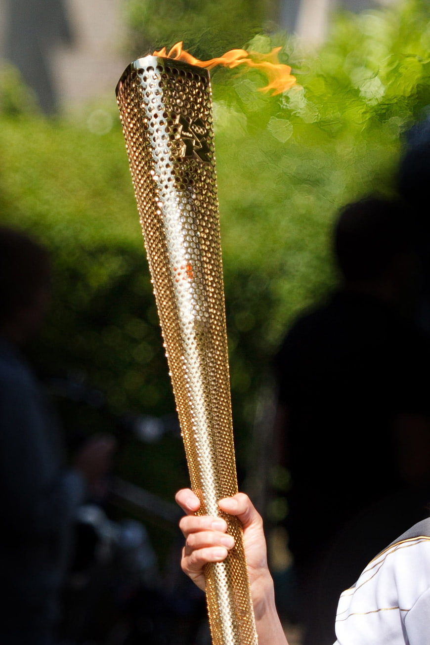 Close-up of hand holding golden Olympic torch with flame