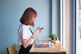 Young Woman Using Smartphone at Wooden Table