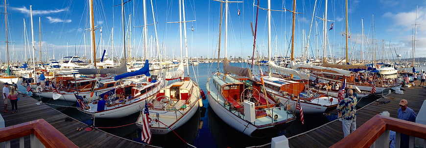 Panoramic view of classic sailboats docked at a sunny marina