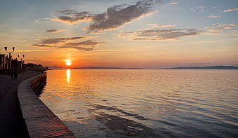 Serene Sunset Over Calm Sea With Curved Promenade