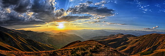 Panoramic Mountain Sunset with Dramatic Sunbeams and Clouds