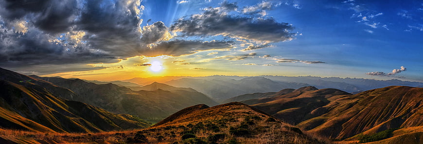 Panoramic Mountain Sunset with Dramatic Sunbeams and Clouds