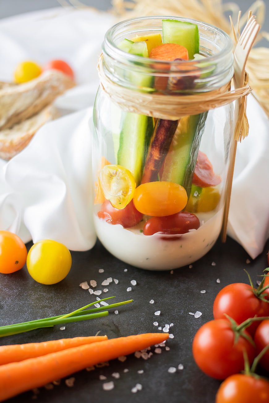 Healthy vegetable salad in glass jar with creamy dressing