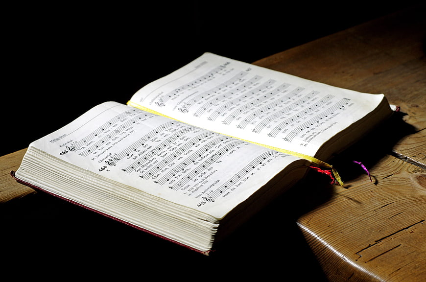 Open Hymn Book on Wooden Table with Sheet Music