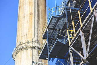 Industrial steel staircase and concrete silo against blue sky