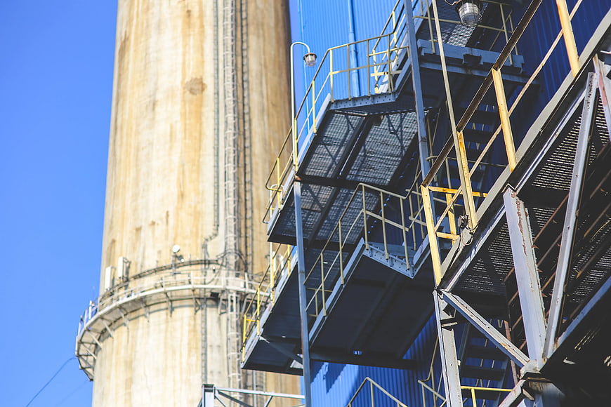 Industrial steel staircase and concrete silo against blue sky