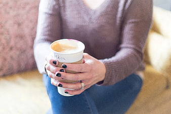 Woman holding coffee cup with black nail polish