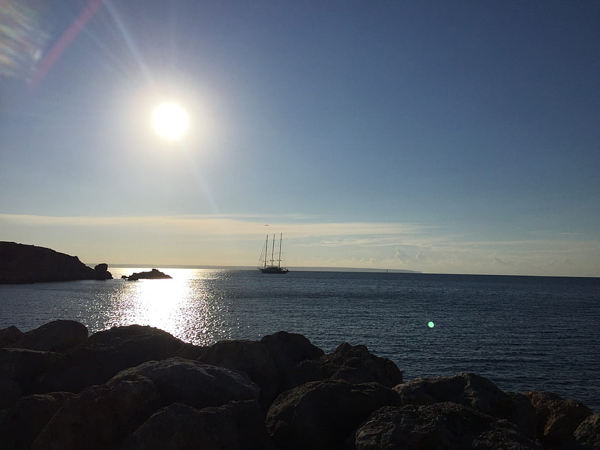 Sailboat Silhouette on Calm Sea with Sun Flare
