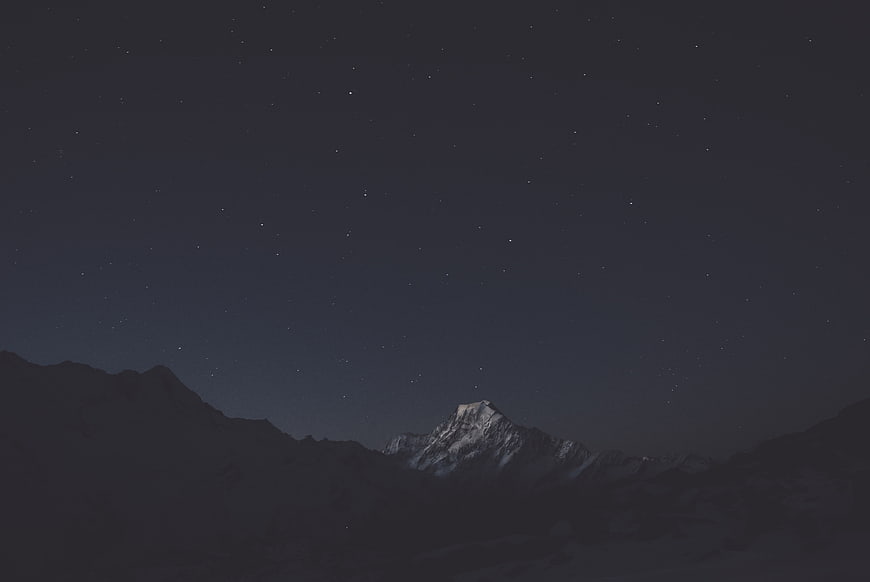Snow-capped mountain peak under a starry night sky