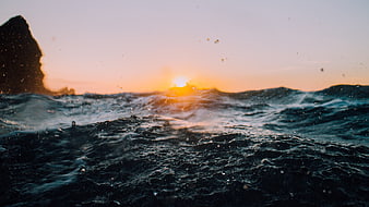 Dramatic Ocean Waves at Sunset with Silhouette Rock