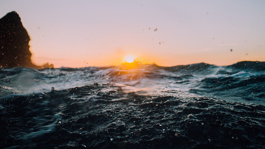 Dramatic Ocean Waves at Sunset with Silhouette Rock