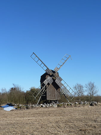 Old wooden windmill in a field under blue sky