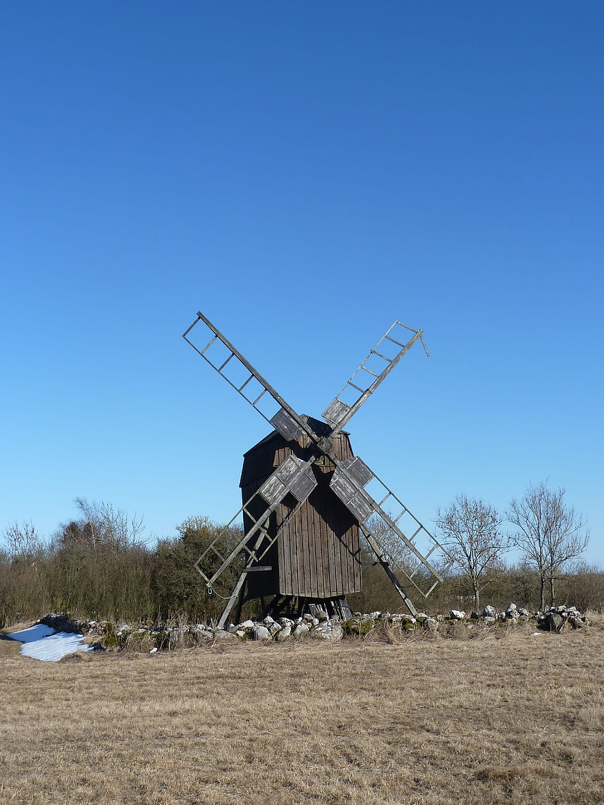 Old wooden windmill in a field under blue sky