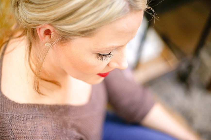 Close-up profile of blonde woman with red lipstick looking down