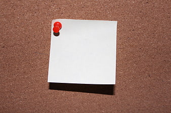 Blank white sticky note pinned to corkboard with red pushpin